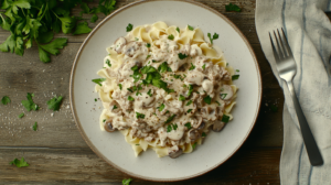 Plate of creamy ground beef stroganoff with egg noodles and mushrooms.